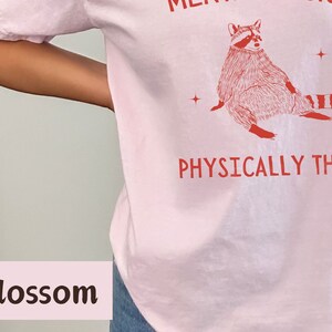 May include: Pink t-shirt with a red raccoon illustration and the text "Mentally a Snack, Physically Thick".