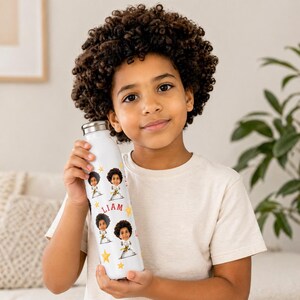 Puede incluir: Botella de agua blanca con tapa plateada, decorada con imágenes de dibujos animados de un niño, estrellas y el nombre "Liam". La botella la sostiene un niño que lleva una camiseta blanca. El diseño se repite a lo largo de la botella.