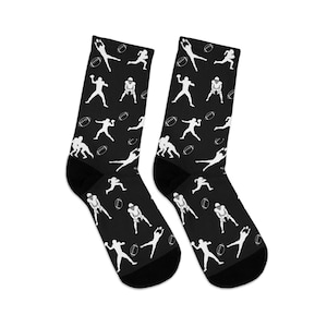 May include: Pair of black socks with a white football player and football pattern. The socks feature a repeating design of football players in various action poses, along with white footballs.
