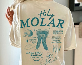 May include: A white t-shirt with a teal blue graphic print of a tooth, dental tools, and the text "Holy Molar", "Oral care is a Human Right", "Have you brushed your teeth?", "Its never too late to improve your smile", and "Smile".