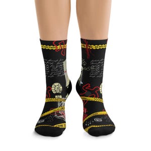 May include: Black socks with a crime scene design. The socks feature yellow police tape, red outlines, footprints, and handwritten text. The words "CRIME SCENE" and "DO NOT CROSS" are visible.