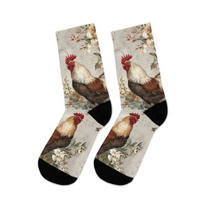May include: A pair of crew socks featuring a vintage-style illustration of a rooster. The rooster has red, brown, and white feathers, and is set against a floral background. The socks have black heels and toes.