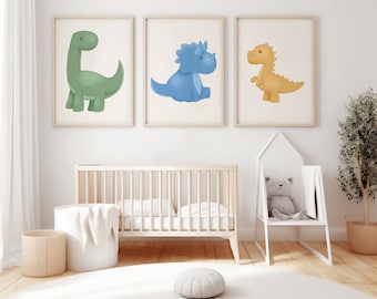 May include: Three framed illustrations of cartoon dinosaurs in a nursery setting. The dinosaurs are green, blue, and yellow. The illustrations are hanging on a white wall above a crib.