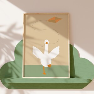 A framed print of a white goose flying a kite, placed on a green cloud-shaped shelf against a light beige wall with shadow patterns. The minimalist artwork features soft earthy tones, perfect for nursery decor.