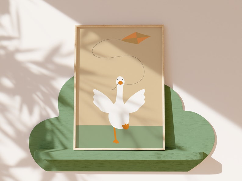 A framed print of a white goose flying a kite, placed on a green cloud-shaped shelf against a light beige wall with shadow patterns. The minimalist artwork features soft earthy tones, perfect for nursery decor.