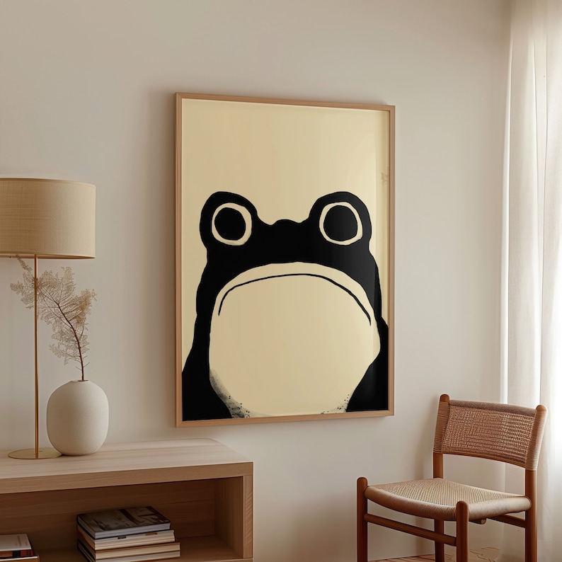 Modern living room with a Matsumoto Hoji Frog Print propped against the wall on a wooden floor, surrounded by houseplants and contemporary furnishings, highlighting the simplicity and charm of Japanese art