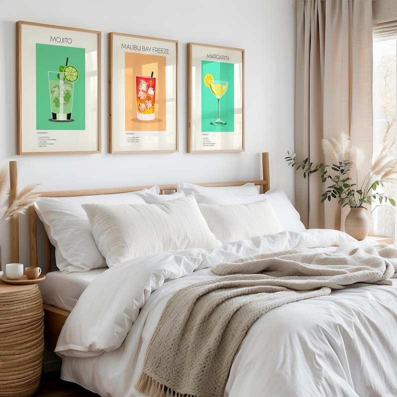 Three framed cocktail prints (Mojito, Malibu Bay Freeze, Margarita) hanging above a cozy bed with white linens, adding a vibrant touch to the bedroom décor.
