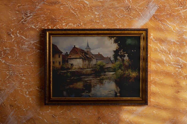 Vintage painting of a rustic European village with reflective river, in a golden frame against a marbled orange wall
