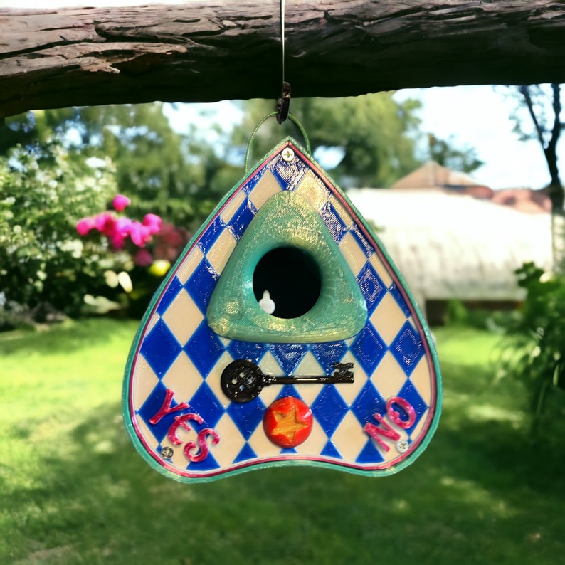 May include: A blue and white triangular birdhouse with a keyhole and the words "YES" and "NO" on the front. The birdhouse is hanging from a branch.