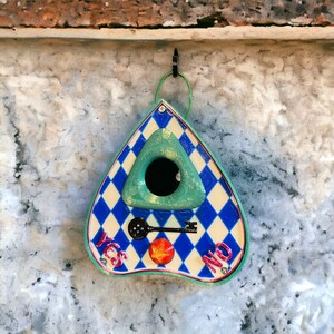 May include: A blue and white triangular shaped wooden birdhouse with a green triangular shaped opening in the front. The birdhouse has the words "YES" and "NO" written on it and a keyhole with a key in it.