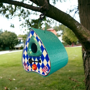 May include: A teal blue birdhouse shaped like a house with a keyhole and a diamond pattern. The birdhouse has the words "Yes" and "No" on it.