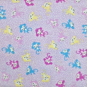 Könnte beinhalten: Ein lila Stoff mit weißen Punkten und einem sich wiederholenden Muster von Affen in verschiedenen Farben, darunter Gelb, Blau, Rosa und Lila.