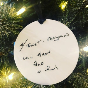 May include: White round Christmas bauble with black handwritten text that reads "To Janet.  Merry Love from  Sno 21"