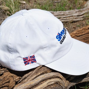 May include: White baseball cap with a blue and white embroidered logo that says "Silverstone Grand Prix" and a small embroidered Union Jack flag.