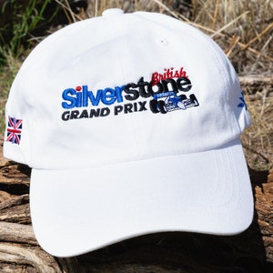 May include: White baseball cap with an embroidered logo that says "Silverstone British Grand Prix" with a red, blue, and black color scheme. The logo also includes a small image of a race car. The cap has a small embroidered Union Jack on the side.