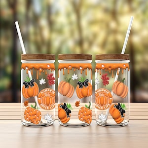May include: Three clear glass tumblers with orange and brown lids. Each tumbler has a design of pumpkins, leaves, and butterflies. The tumblers have the text "Pumpkin Spice Life" on them.