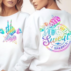 Może przedstawiać: Biała bluza z kolorowym motywem szkieletu ręki podnoszącej sztangę i kwiatów. Tył bluzy przedstawia szkielet ze sztangą i napis "I DON'T SWEAT I SPARKLE" w tęczowych kolorach.
