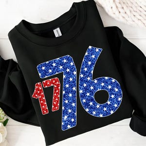May include: Black sweatshirt with a red and blue glitter design of the number 1776. The numbers are made up of white stars on a red and blue background.