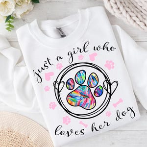 May include: White sweatshirt with the text "just a girl who loves her dog" and a colorful paw print graphic.