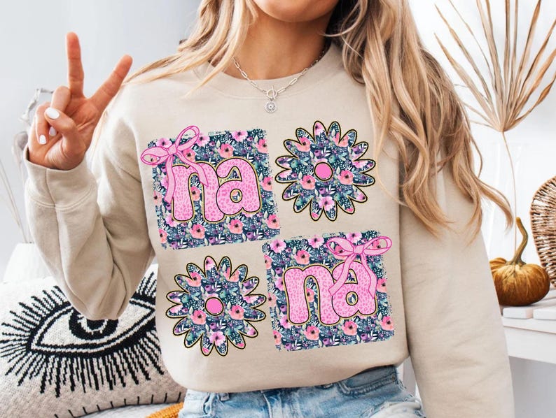 May include: A beige sweatshirt with a floral design and the word "nana" printed in pink letters.