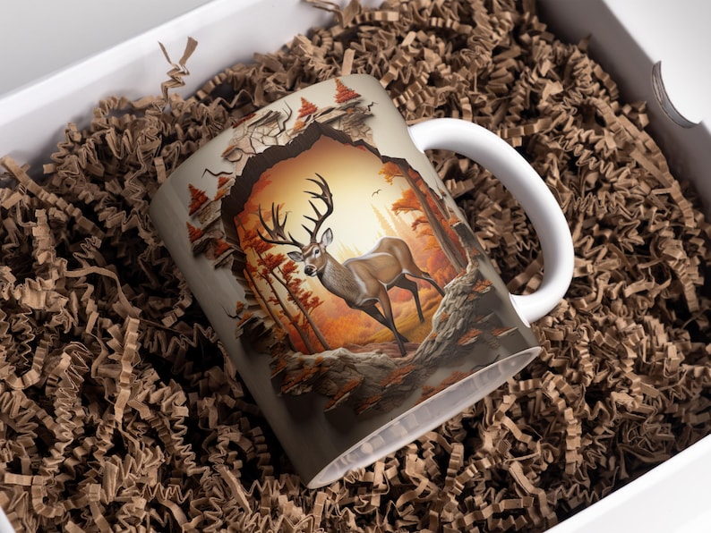 May include: A white ceramic mug with a 3D image of a deer standing in a forest. The deer is brown with large antlers and is surrounded by trees and leaves. The mug has a handle on the right side.