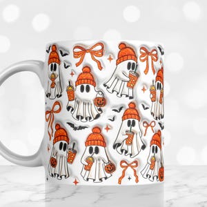 May include: White ceramic mug with a repeating pattern of cartoon ghosts wearing orange beanies, holding pumpkin-shaped lanterns and iced coffee. The design includes orange bows and black bats, perfect for Halloween.