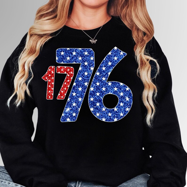 May include: Black sweatshirt with a red and blue glitter design of the number 1776. The numbers are made up of white stars on a blue background.