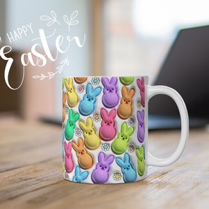 May include: White ceramic mug with a colorful pattern of pastel-colored bunny-shaped candies. The mug has a handle and says "Happy Easter" in white lettering.