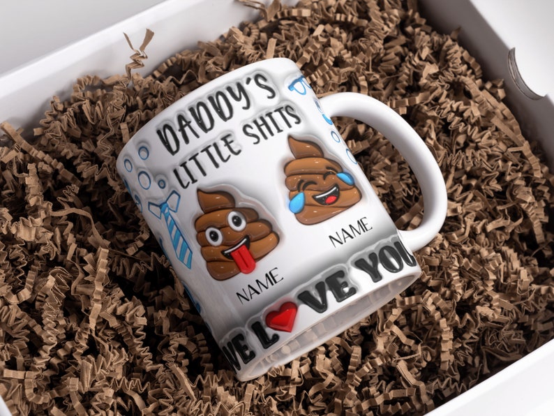 K&ouml;nnte beinhalten: Wei&szlig;e Keramiktasse mit einem schwarzen und braunen Design. Die Tasse tr&auml;gt den Text "Daddy's Little Shits" und zwei Kack-Emojis. Der Text "We Love You" befindet sich am Boden der Tasse.