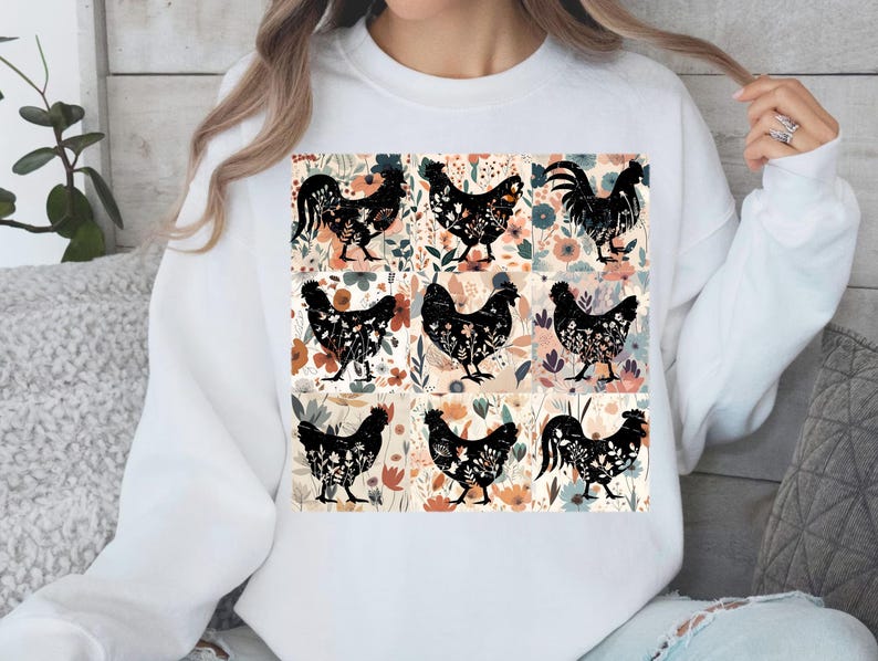 May include: White sweatshirt featuring a colorful floral and chicken design. The design includes nine black chicken silhouettes filled with floral patterns, set against a backdrop of flowers in various colors.
