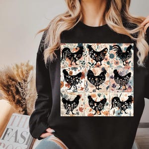 May include: Black sweatshirt featuring a nine-panel design with floral backgrounds and black chicken silhouettes. The chickens are in various poses. The sweatshirt is a solid black color.