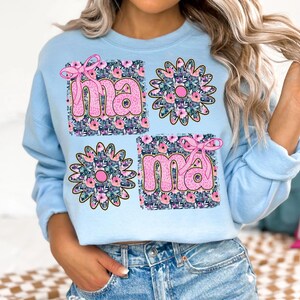 May include: Light blue sweatshirt with a floral design and the word "mama" in pink letters.