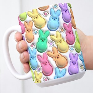May include: White ceramic mug with a colorful pattern of pastel-colored bunny shapes. The bunnies are arranged in a repeating pattern and have a 3D effect.