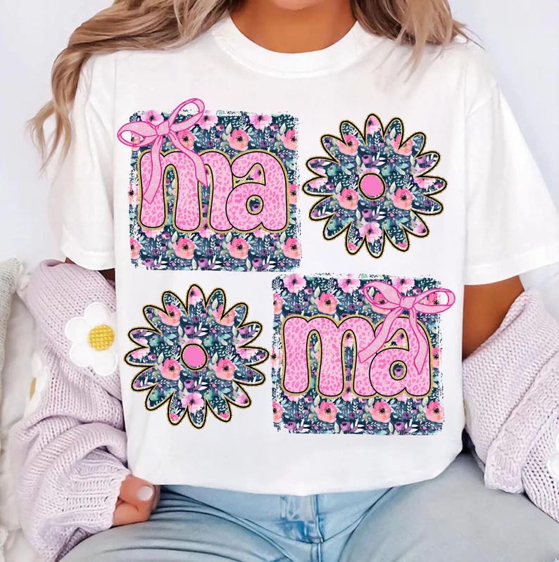 May include: White t-shirt with a pink and gold floral design and the word "mama" printed twice in pink letters.