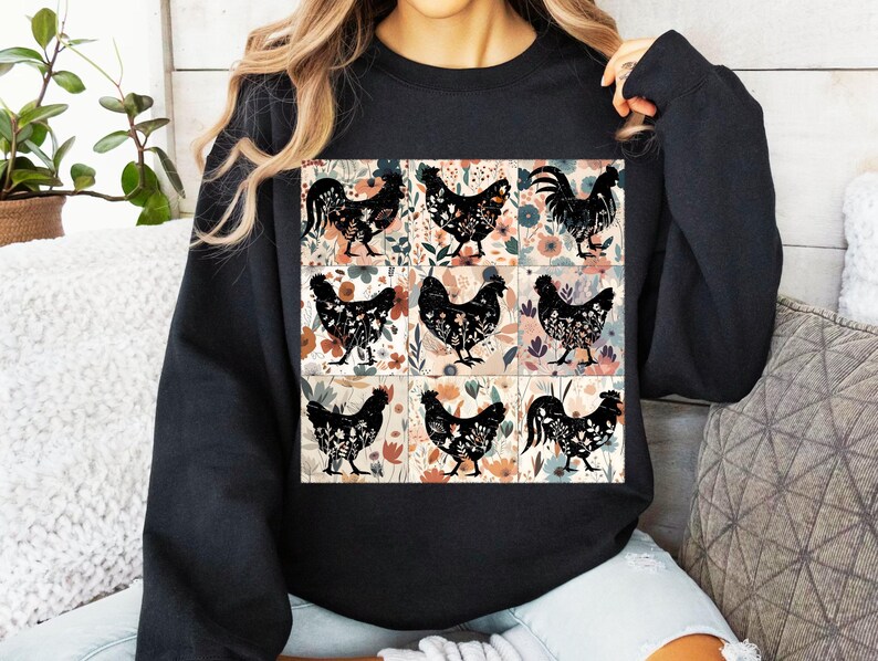 May include: Black sweatshirt featuring a nine-panel design with black rooster and hen silhouettes. Each panel has a floral background in shades of pink, orange, and green. The sweatshirt is a solid black color.