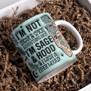 Puede incluir: Una taza de cerámica azul claro con asa blanca. La taza tiene un diseño en blanco y negro con el texto "I'm not sugar & spice & everything nice I'm sage & hood & I wish a mfer would".
