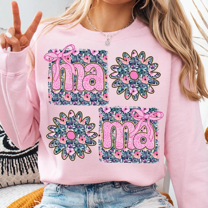 May include: Pink sweatshirt with a floral design and the word "mama" in pink letters.