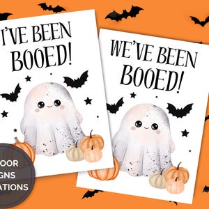 May include: Two Halloween door signs with a white background and orange accents. Each sign features a cute ghost illustration, pumpkins, bats, and the phrases "I've Been Booed!" and "We've Been Booed!" in black text. Ideal for Halloween.
