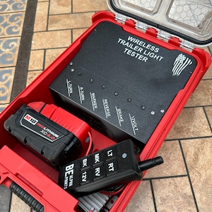 以下が含まれることがあります： 赤色の、開いた防水ケース。中には黒色のワイヤレスのトレーラーライトテスター、赤と黒のバッテリー、黒色のリモコンが入っています。テスターには「WIRELESS TRAILER LIGHT TESTER」の文字。リモコンには「LT RT MK RV BK 12V」の文字。