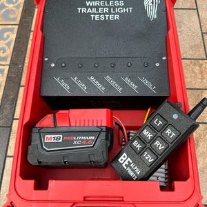 Pu&ograve; includere: Un kit tester per luci per rimorchi wireless rosso. Il kit include un pannello di controllo nero con pulsanti etichettati e un telecomando. Il kit include anche una batteria rossa M18 REDLITHIUM XC4.0.