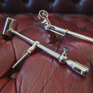 Könnte beinhalten: Zwei polierte, silberfarbene Metallbeschläge mit verstellbaren Armen, Kugelgelenken, Gewindeschrauben und einem federbelasteten Klemmmechanismus. Diese mechanischen Teile sind mit einer glatten, reflektierenden Oberfläche versehen und verfügen über verschiedene Feststellschrauben für eine präzise Positionierung und sichere Befestigung.