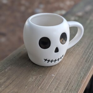 May include: A set of three ceramic mugs with a speckled, matte finish. The mugs are in shades of cream, light gray, and dark gray. Each mug has a simple, minimalist design and a rounded handle.