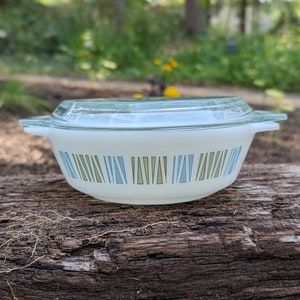 May include: A white casserole dish with a glass lid. The dish has a geometric pattern of blue, green, and white triangles.