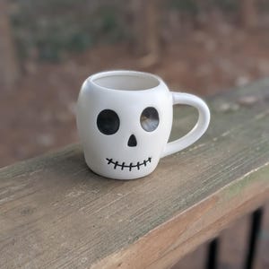 May include: A set of three ceramic mugs with a speckled, matte finish. The mugs are in shades of cream, light gray, and dark gray. Each mug has a simple, modern design and a rounded handle.