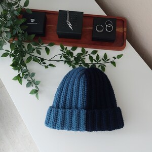 May include: A blue and dark blue knitted beanie hat with a ribbed texture.