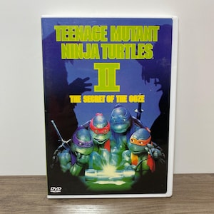 May include: DVD case for "Teenage Mutant Ninja Turtles II: The Secret of the Ooze." The cover features the four turtles with colored masks, set against a dark blue background. The title is in yellow and green.