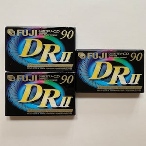 May include: Three black cassette tapes with a blue and yellow design. The tapes are labeled "FUJI Cassette for CD DR II 90" and feature the text "Extraslim case / Boîtier extra-mince IEC/TYPE II HIGH POSITION/POSITION ÉLEVÉE".