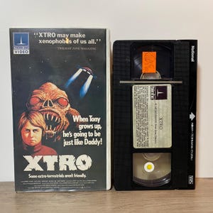 May include: A VHS video cassette and its case for the film "XTRO." The case shows an alien and a boy, with the text "When Tony grows up, he's going to be just like Daddy!" and "Some extra-terrestrials aren't friendly."