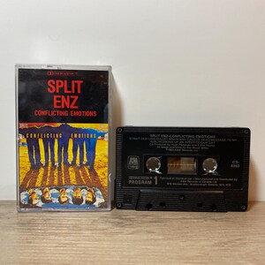 May include: A Split Enz "Conflicting Emotions" cassette tape and its case are shown. The case has a vibrant design with the band's name. The black cassette tape displays the album title and song list. A vintage music item.