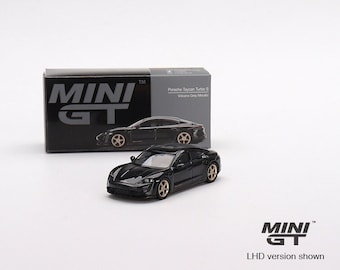 May include: Black Porsche Taycan Turbo S diecast model car with gold wheels. The car is on a white surface with a black box behind it. The box has the text "MINI GT" and "Porsche Taycan Turbo S Volcano Grey Metallic" on it.
